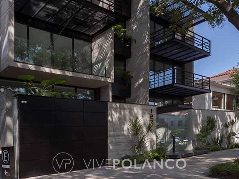 Fachada de casa moderna con muros de concreto, grandes ventanales, balcones metálicos y vegetación en Aristoteles 128, Polanco