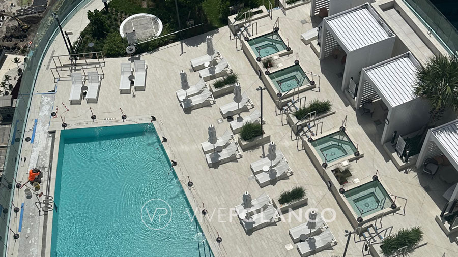 Bird's-eye view of a luxurious rooftop pool and cabana area in a modern high-rise condo complex