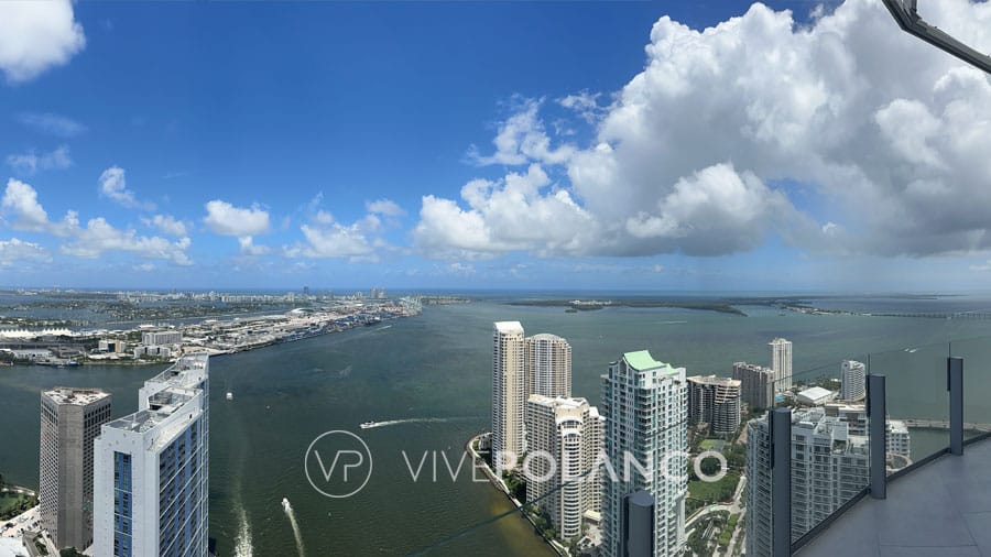 Panoramic view from a high-rise luxury condo balcony, overlooking the city and waterfront.