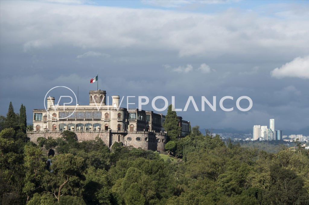 Chapultepec Castle on a hilltop surrounded by trees, with a view of Mexico City in the background.