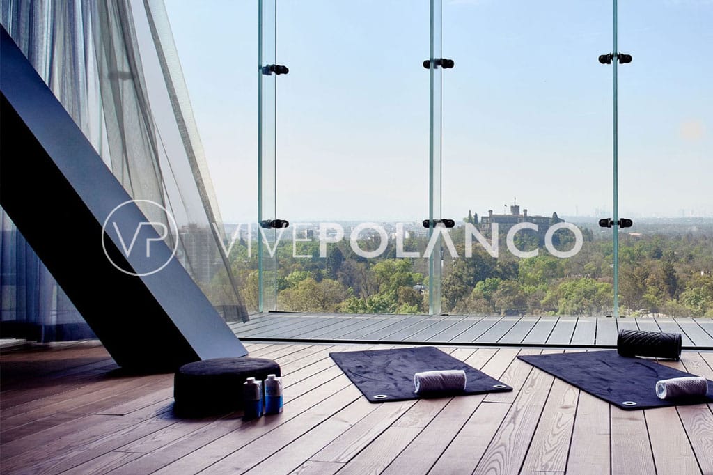 Modern meditation room with expansive glass walls overlooking a city park, designed for relaxation and wellness.