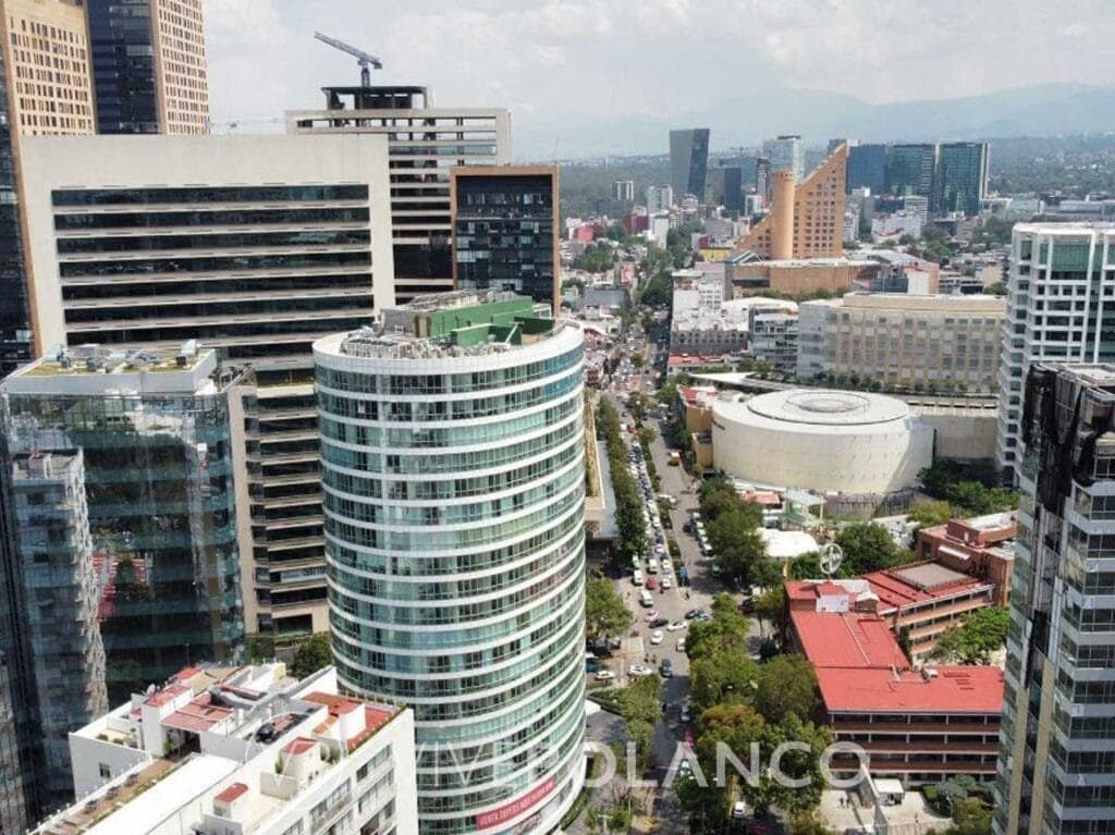 Vista aérea de Nuevo Polanco con edificios modernos, torre cilíndrica y calles arboladas en CDMX