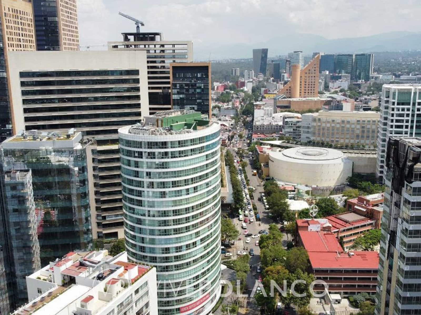 Vista aérea de Nuevo Polanco con torres residenciales modernas, torre cilíndrica corporativa y calles arboladas