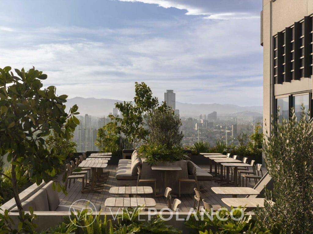 Terraza exterior Be Grand Reforma con mobiliario de madera, plantas y vista panorámica del skyline en Be Grand Reforma Cdmx, Polanco