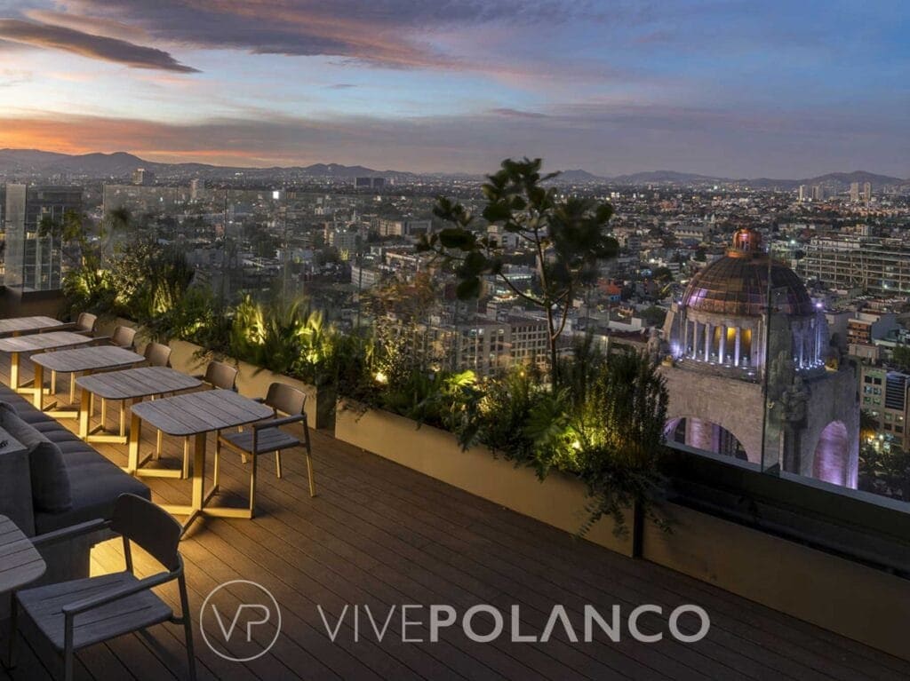 Terraza en rooftop de Be Grand Reforma con mesas altas y vista panorámica de Ciudad de México al atardecer en Be Grand Reforma Cdmx, Polanco