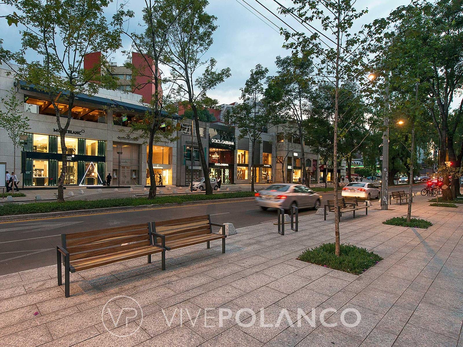 Vista nocturna de avenida comercial con tiendas de lujo y banquetas arboladas en Nuevo Polanco