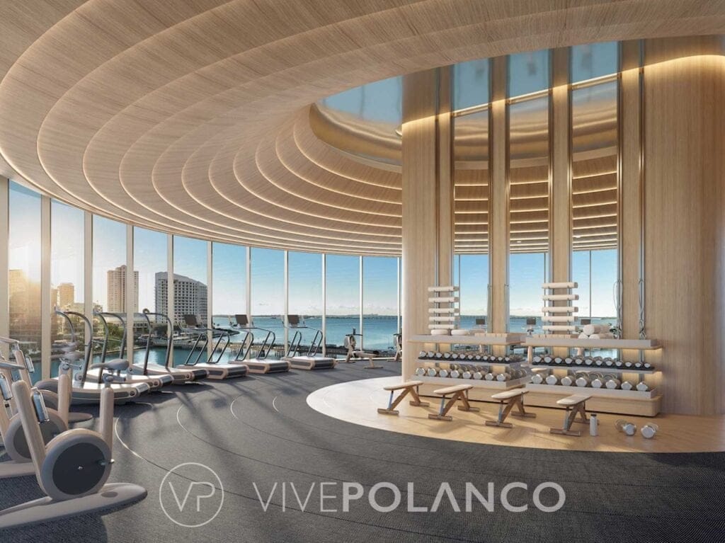Gimnasio de lujo con ventanales panorámicos, techo de madera curvado, equipos de ejercicio y vista al océano