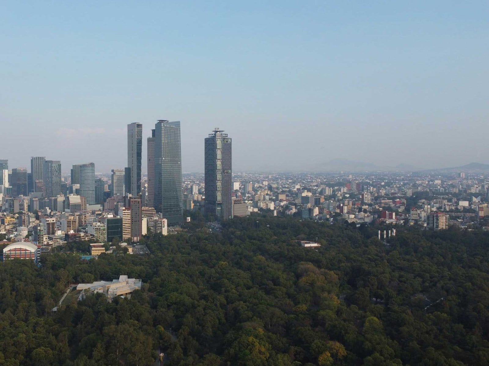 Panorámica aérea mostrando rascacielos modernos, extensas áreas verdes arboladas y desarrollo urbano en Green Chapultepec Park, Polanco