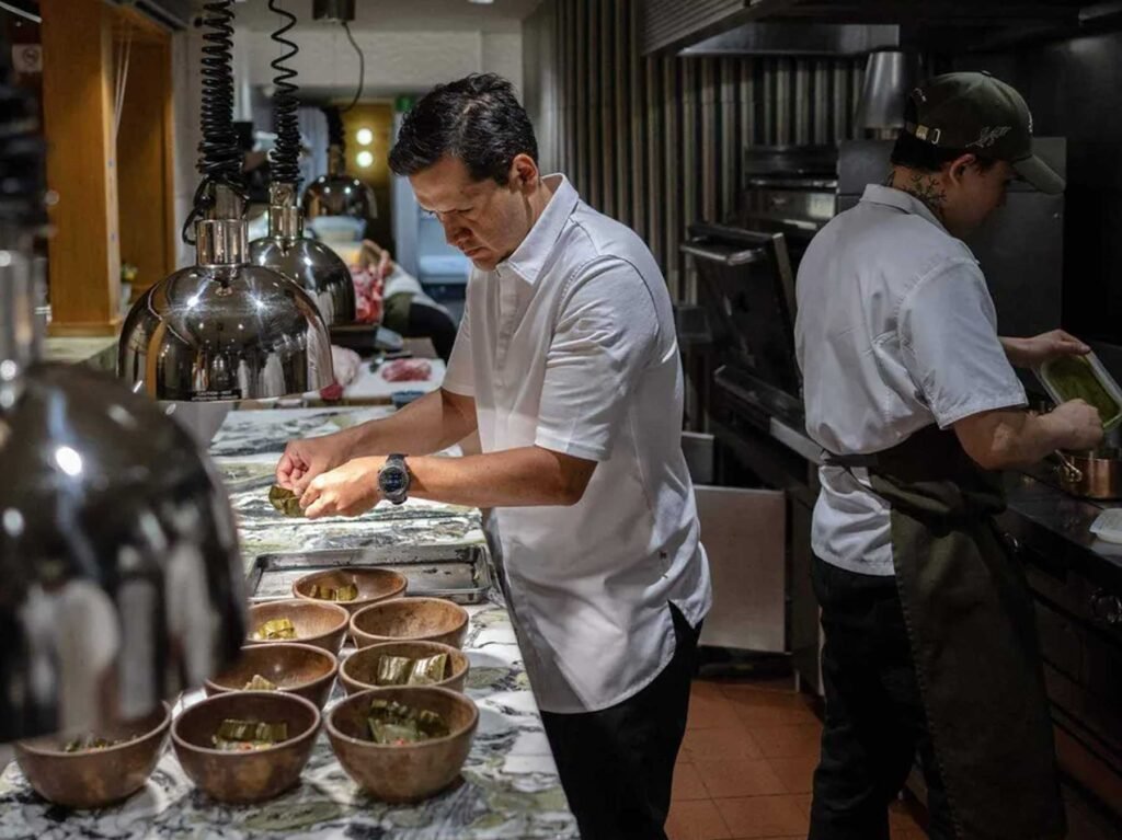 Dos chefs trabajando en cocina profesional con bowls de madera y superficie de mármol en Quintonil Polanco, Polanco