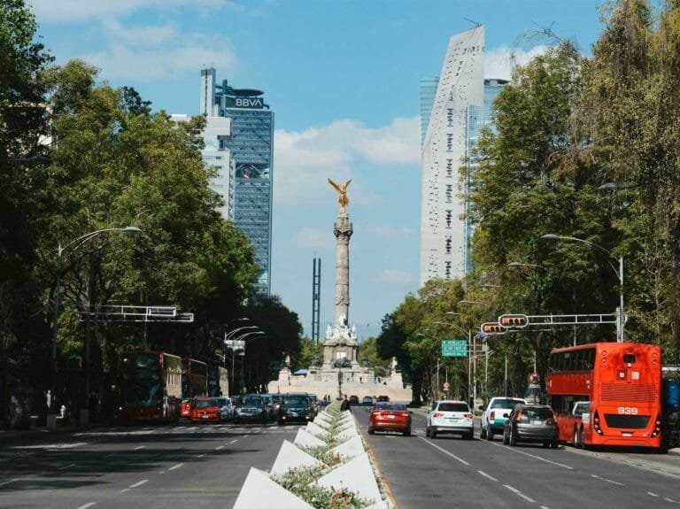 Avenida con monumento central, edificios corporativos al fondo y tráfico vehicular en ciudad en Reforma Angel Cdmx, Polanco