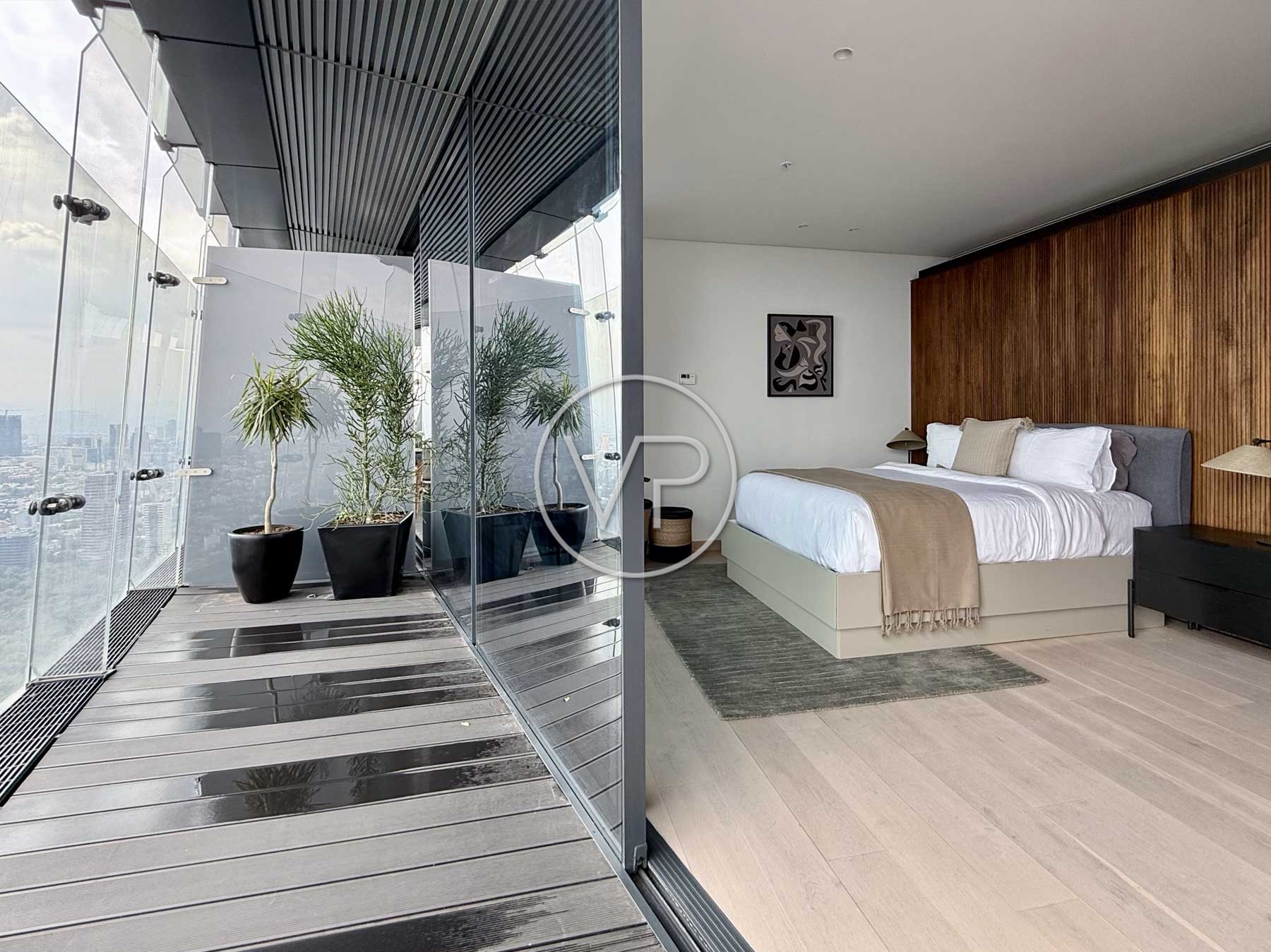 Terraza con macetas y barandal de vidrio junto a una recámara con cama blanca y muro de madera en Polanco
