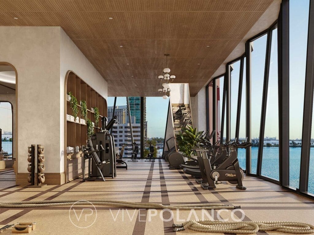 Gimnasio moderno con equipos de ejercicio y ventanales panorámicos con vista al agua y ciudad en Villa Miami Residences, Polanco