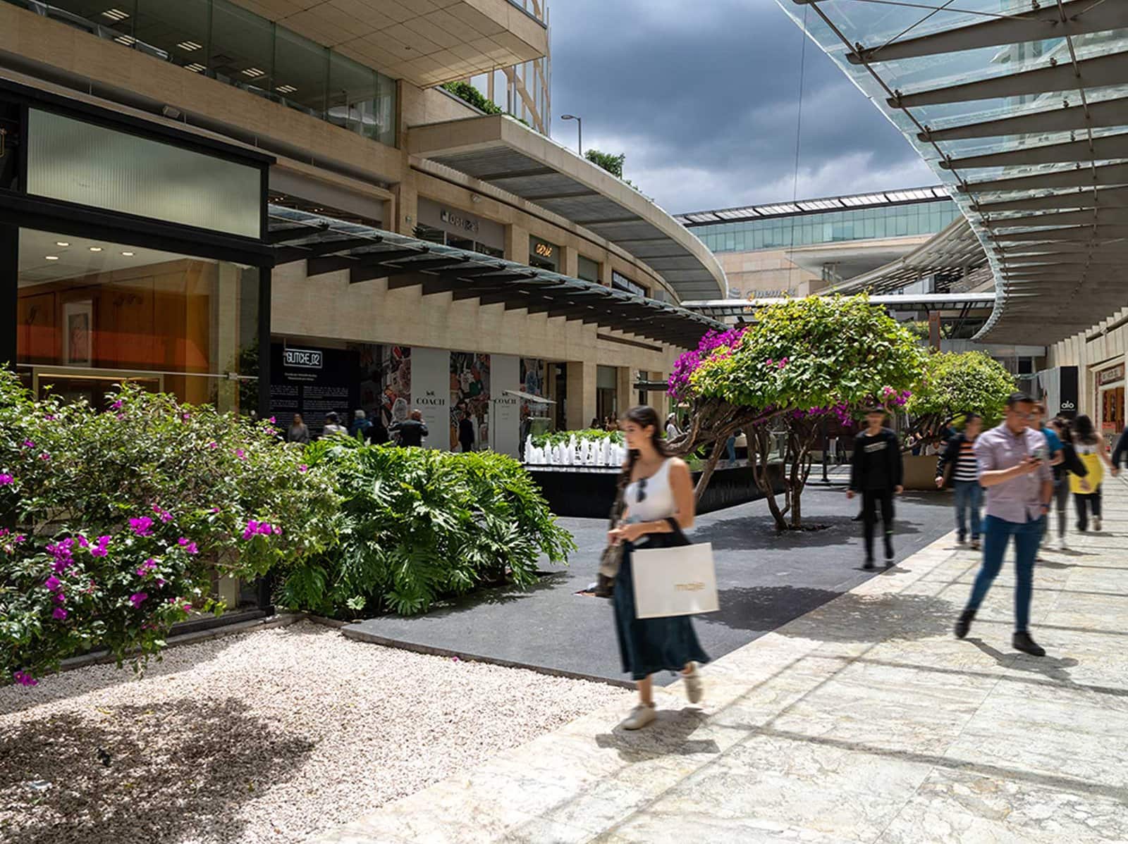 Pasillos peatonales de Plaza Antara Polanco con jardineras, tiendas y estructura de vidrio