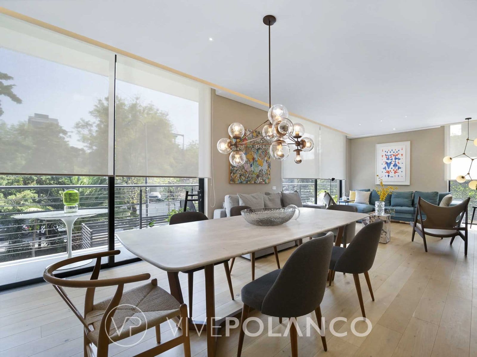 Comedor y sala con ventanales hacia los árboles en un departamento de Avenida Homero, Polanco