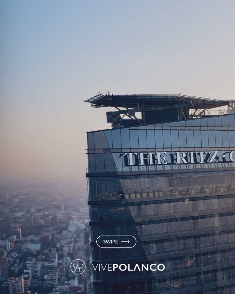 Vista aérea de edificio residencial de lujo con fachada de cristal y helipuerto en la azotea durante el atardecer