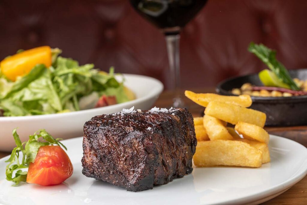 Corte a la brasa con papas fritas y ensalada en DANTE Brasa y Fuego